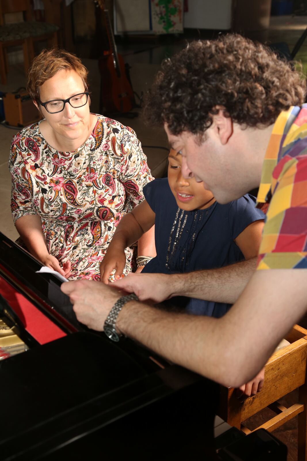 Ben at the piano with a student and her teacher, guiding her through a piece