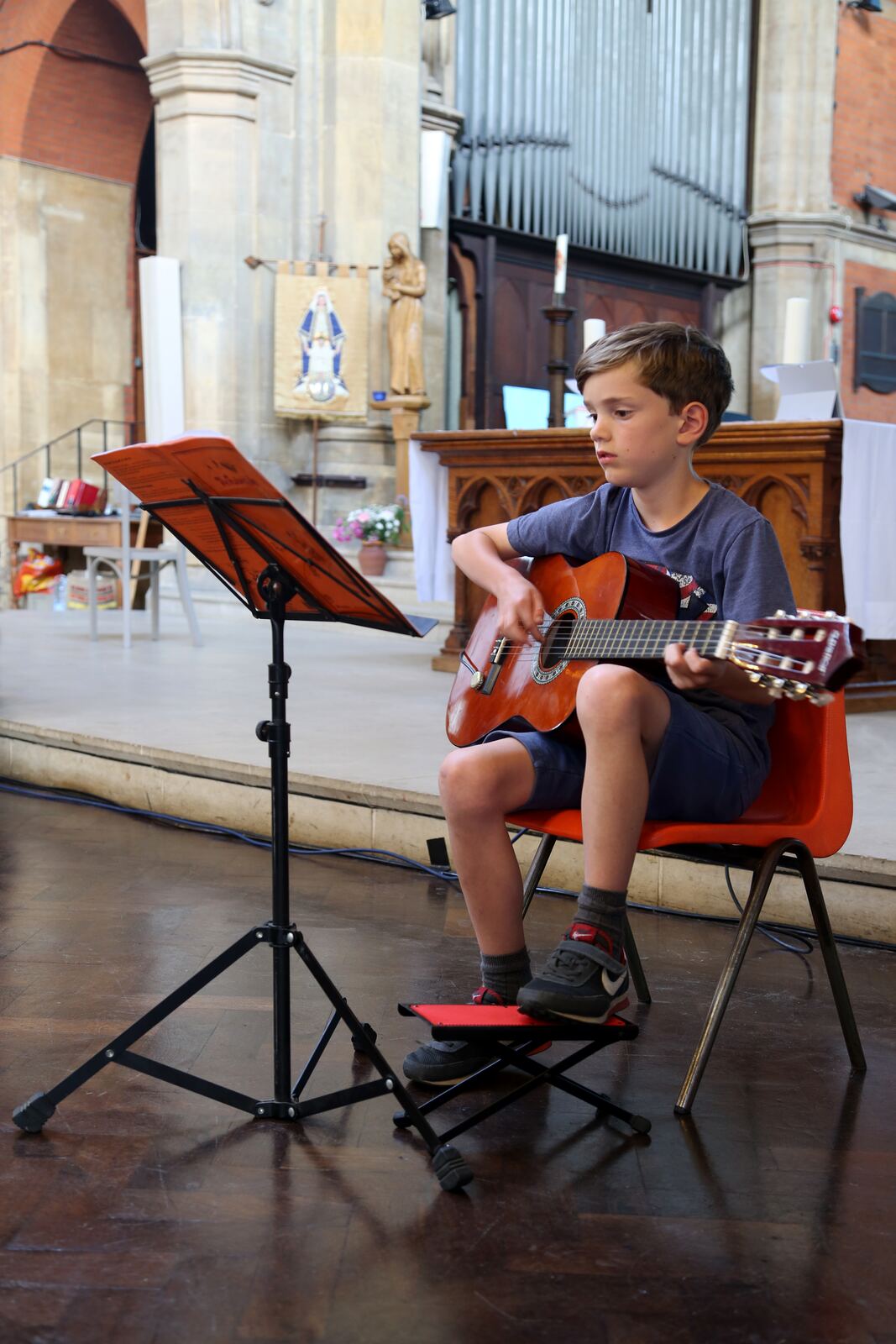 A boy playing classical guitar from a music stand