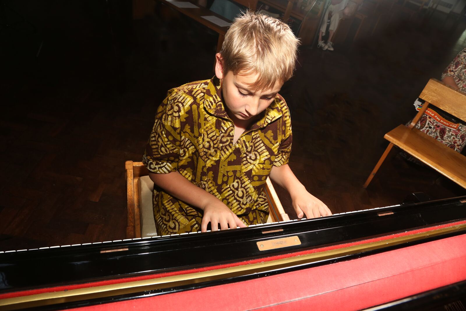 A boy at the keys of a grand piano, seen from above