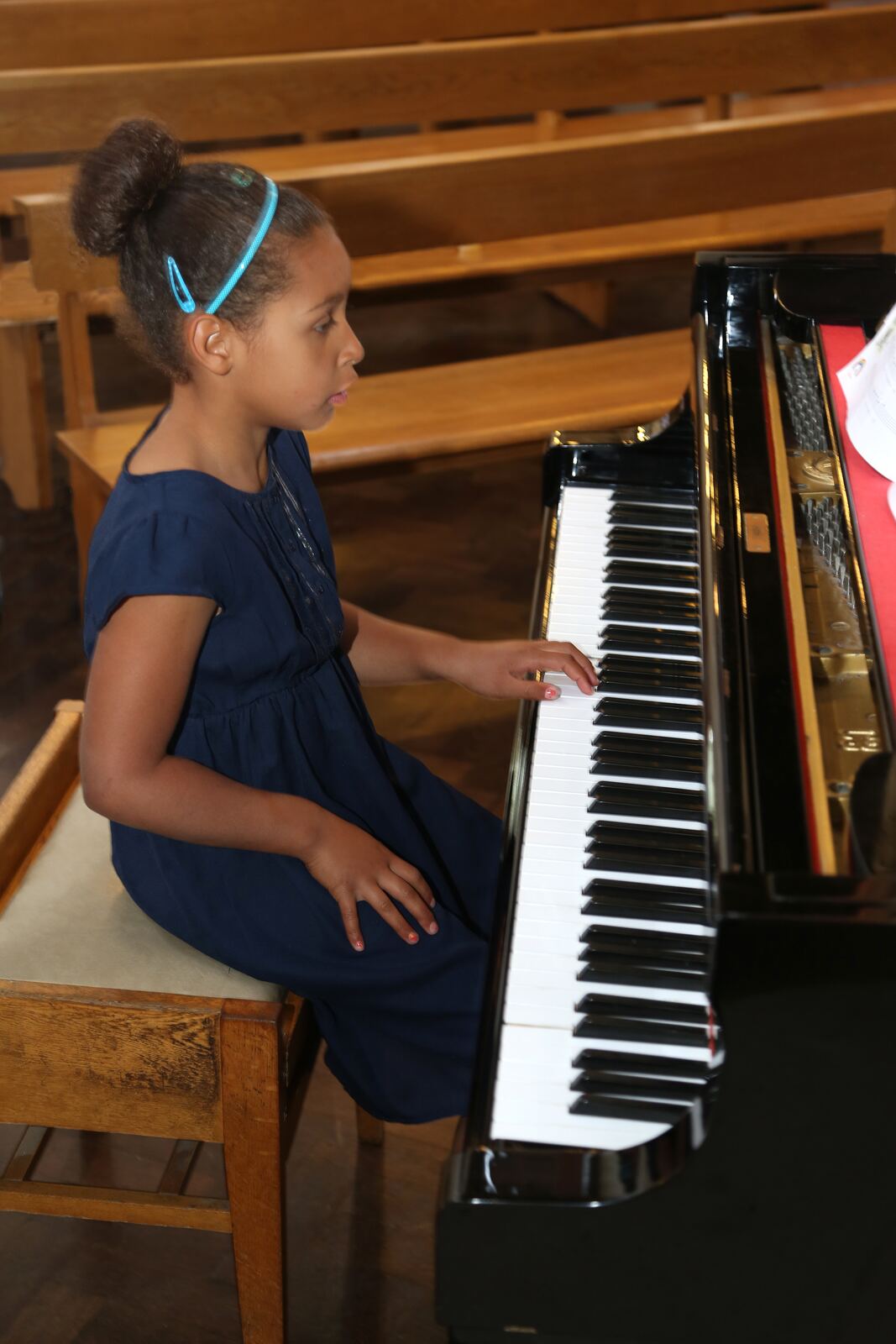A girl playing a grand piano, seen from the side